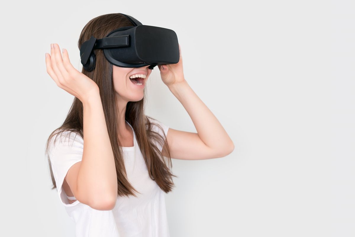 Young woman wearing virtual reality goggles headset, vr box. Connection, technology, new generation, progress concept. Girl trying to touch objects in virtual reality. Studio shot on gray